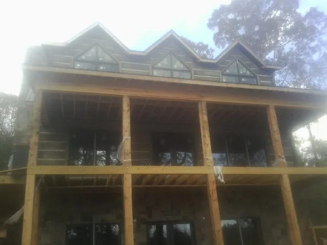Dormers and porch framing on a large log home under construction — Roof Coating work by our crew in Elk Horn