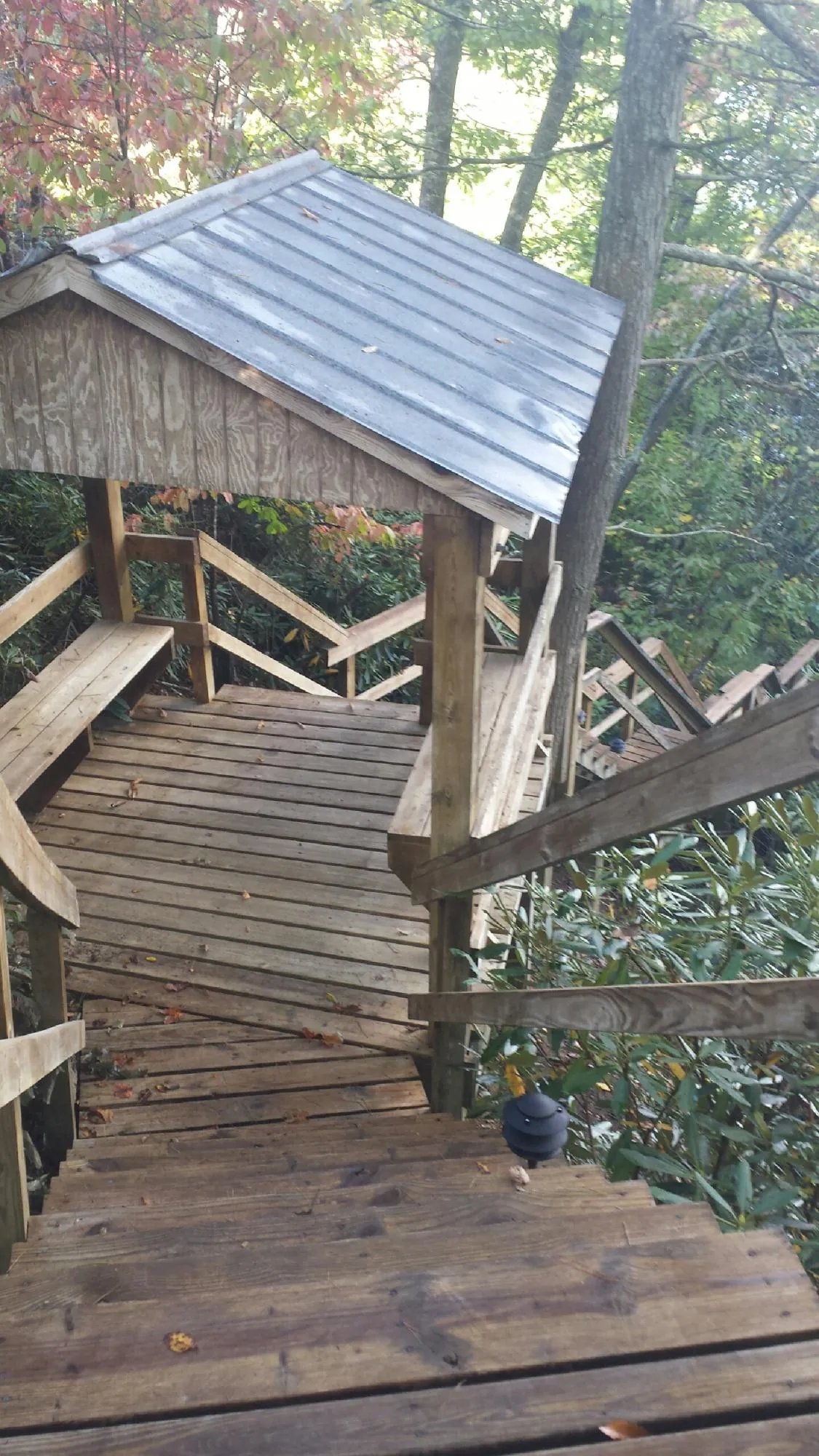 Metal roofed shelter over wooden steps on a wooded walkway — Skylight Repair & Installation work by our crew in Elk Horn