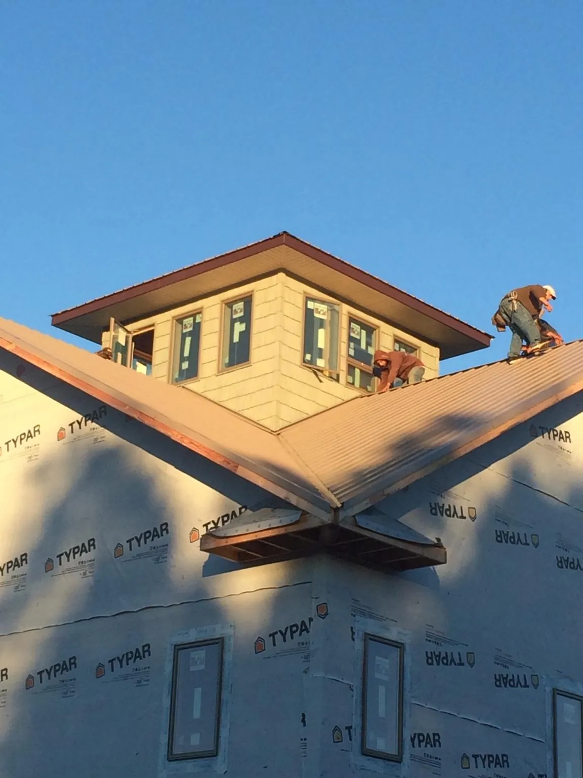 Roofers working around a rooftop cupola on a new metal roof at sunset — Roof Waterproofing in Elk Horn by Roofing Brothers
